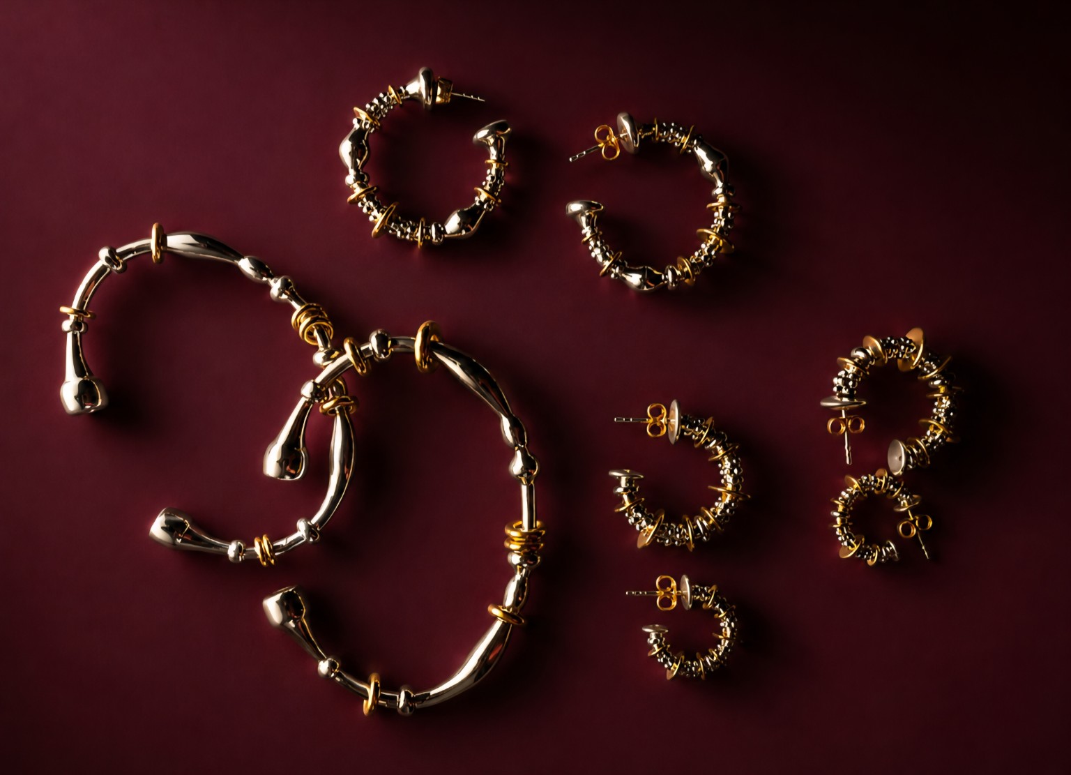 Gold jewelry pieces on burgundy background